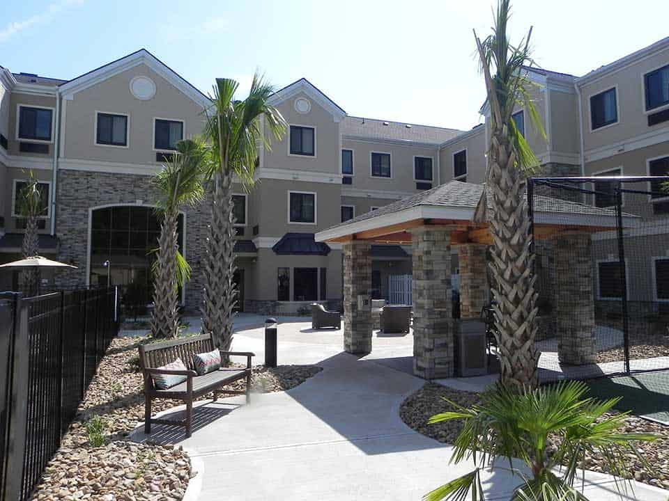Modern residential complex with landscaped courtyard and palm trees.